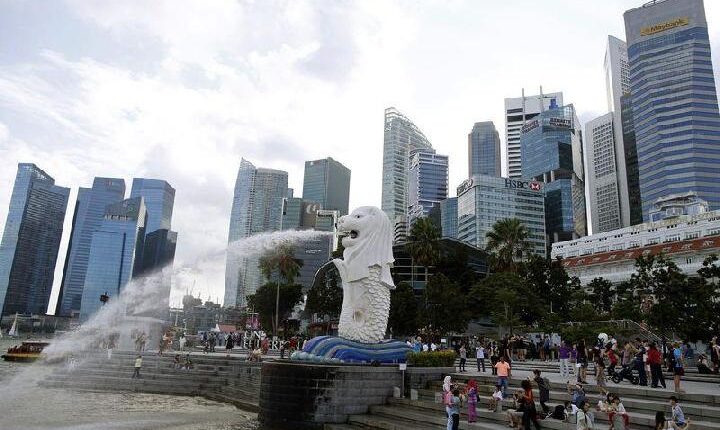 Turis berfoto di sebelah patung singa Merlion di kawasan pusat bisnis Singapura 6 Februari 2015. [REUTERS / Edgar Su]