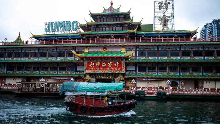 Foto: Sebuah perahu sampan melewati Restoran Terapung Jumbo yang terletak di dekat Aberdeen di sisi selatan pulau Hong Kong, Senin (13/6/2022). (Photo by BERTHA WANG/AFP via Getty Images)