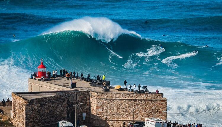 Peselancar mencoba menaklukkan ombak raksasa dekat Benteng Mercusuar Nazare di Nazare, Portugal. Nazare terkenal di kalangan peselancar karena memiliki ombak-ombak terbesar di dunia.(Dok. Shutterstock/R.M. Nunes)