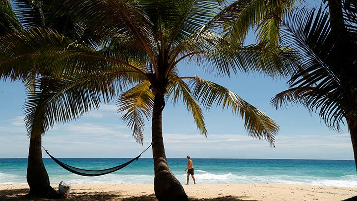 Seorang pria berjalan di pantai Karon saat Phuket bersiap-siap untuk dibuka untuk turis asing mulai 1 Juli yang mengizinkan orang asing yang divaksinasi penuh untuk mengunjungi pulau resor tanpa karantina, Phuket, Thailand 29 Juni 2021. Berdasarkan keterangan resmi dari Tourism Authority of Thailand (TAT), wisatawan yang diizinkan masuk ke Phuket hanya mereka yang berasal dari negara dan wilayah yang telah disetujui oleh Badan Penanggulangan Covid-19 Thailand (Centre for Covid-19 Situation Administration atau CCSA). REUTERS/Jorge Silva