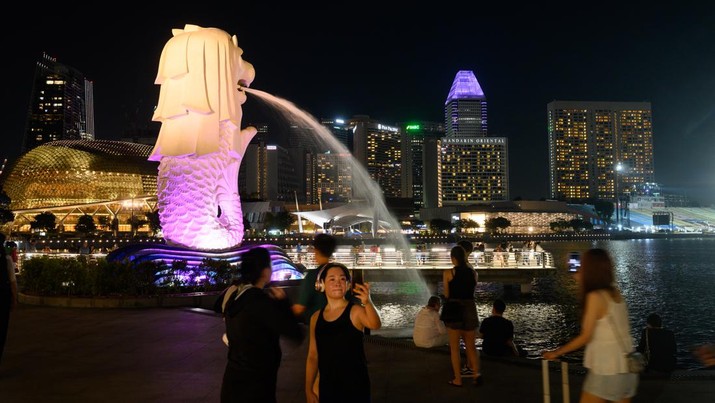 Foto: Warga berswafoto di patung Merlion Singapura ditengah lonjakan kasus Covid. (picture alliance via Getty Images)