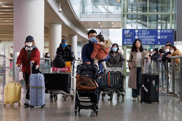 Penumpang mendorong bagasi mereka melalui aula kedatangan internasional di Bandara Internasional Ibukota Beijing setelah China mencabut persyaratan karantina COVID-19 untuk pelancong yang datang di Beijing, China 8 Januari 2023. REUTERS/Thomas Peter