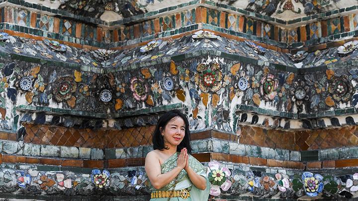 Wisatawan asal Cina, Shuhui Xu (43) mengenakan kostum tradisional Thailand saat mengunjungi kuil Wat Arun menjelang Tahun Baru Imlek di Bangkok, Thailand 18 Januari 2023.