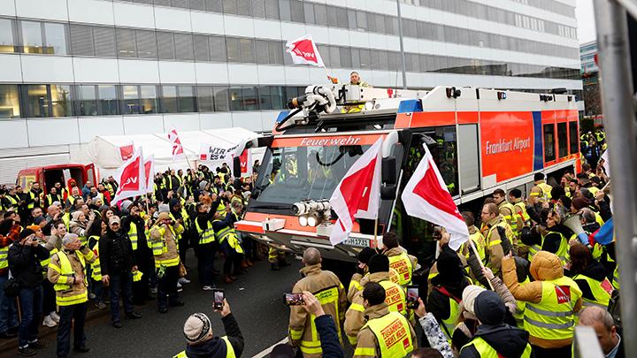 Seorang pria mengibarkan bendera di atas kendaraan, saat para pekerja mogok, setelah serikat buruh Jerman Verdi meminta para pekerja di bandara Frankfurt, Munich, Stuttgart, Hamburg, Dortmund, Hanover dan Bremen untuk melakukan pemogokan 24 jam, di Frankfurt, Jerman Februari 17, 2023. REUTERS/Heiko Becker