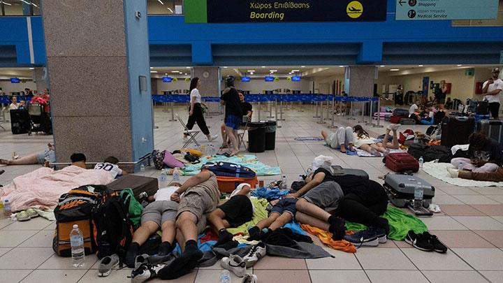 Wisatawan tertidur saat menunggu pesawat berangkat di bandara, setelah dievakuasi menyusul kebakaran hutan di pulau Rhodes, Yunani, 24 Juli 2023. Pemadam kebakaran mengatakan 19.000 orang dipindahkan dari rumah dan hotel. REUTERS/Nicolas Economou