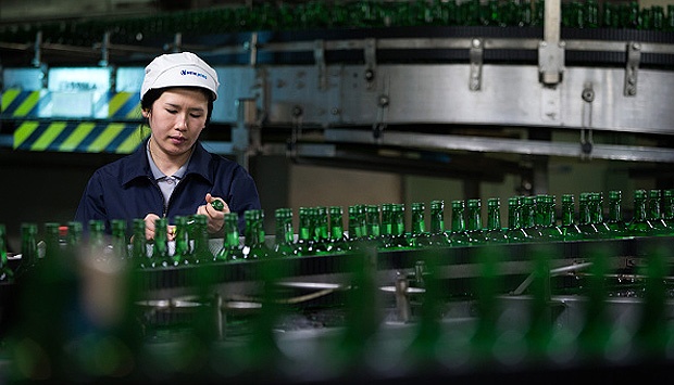 Seorang pegawai tengah memeriksa kondisi botol di Hite Jinro Co. factory di Icheon, Korea Selatan. Hite Jonru merupakan pabrik terbesar pembuatan minuman berjenis Liquor atau dikenal disana dengan nama Soju, 22 Desember 2014. SeongJoon Cho/Bloomberg via Getty Images.