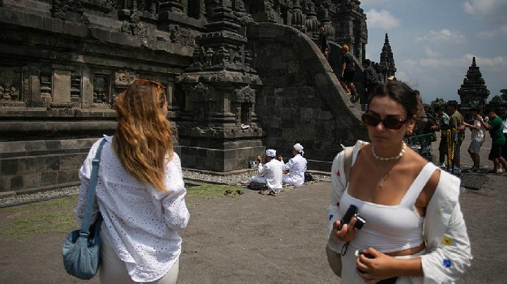 Wisatawan mancanegara melintasi umah Hindu yang berdoa di kompleks Taman Wisata Candi Prambanan, Sleman, DI Yogyakarta, Rabu, 2 Oktober 2024. Badan Pusat Statistik mengungkap sepanjang Januari hingga Agustus 2024 total kunjungan wisatawan mancanegara mencapai 9.092.856 orang meningkat 20,38 persen dibandingkan periode yang sama pada lalu dan menjadi kunjungan tertinggi sejak 2020. ANTARA/Hendra Nurdiyansyah